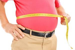 Homem gordo medindo a barriga com fica métrica