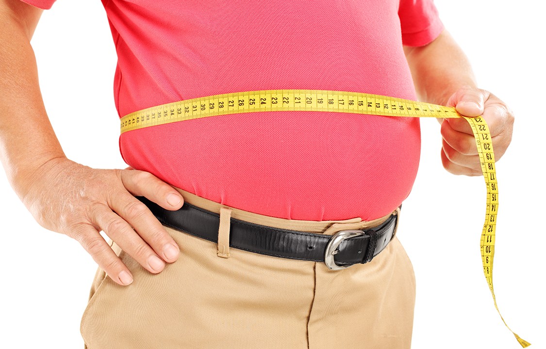 Homem gordo medindo a barriga com fica métrica