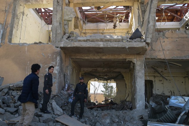 Guardas afegãos caminham sobre os destroços de um distrito policial em Cabul, após um ataque com carro bomba, no Afeganistão