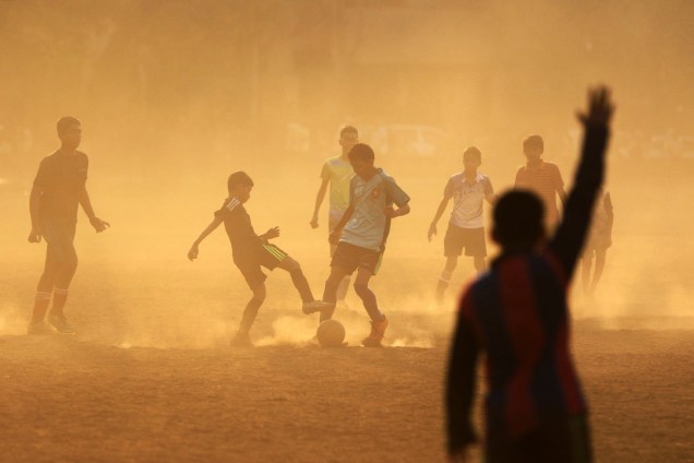 Meninos disputam a bola durante uma partida de futebol em Mumbai, na Índia
