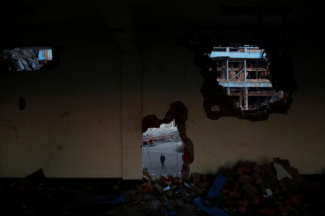 Homem é visto através de um buraco em uma parede demolido na região de Hangzhou, na China - 02/03/2017