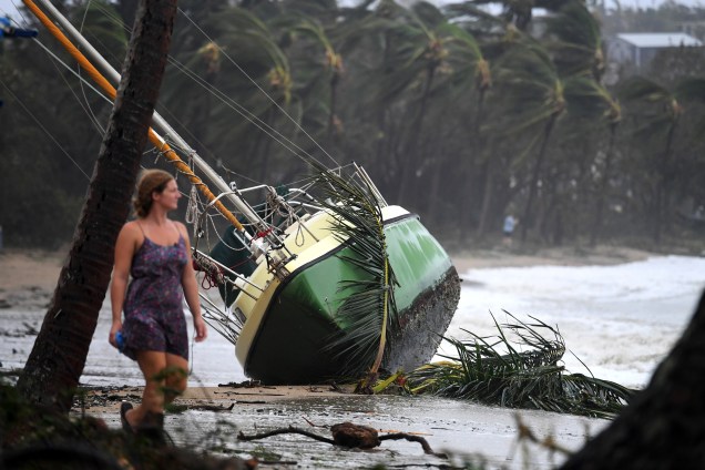Mulher passa por um barco arrastado para a terra depois que o ciclone Debbie atingiu a cidade de Airlie Beach, no sul de Townsville, na Austrália - 29/03/2017