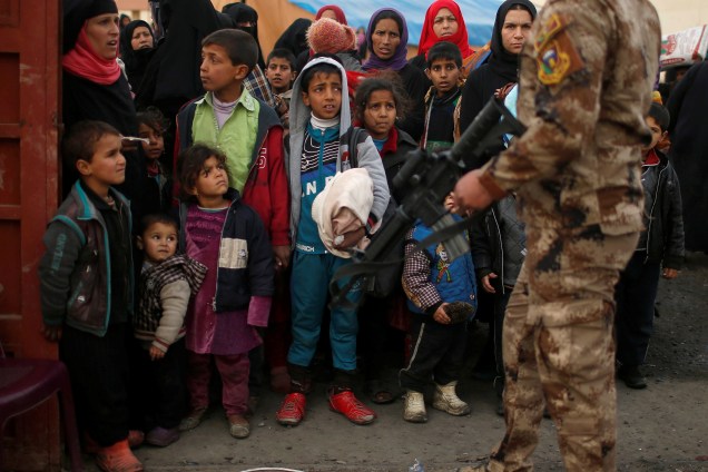 Crianças desabrigadas aguardam para serem transportadas para um local seguro durante os combates entre as forças de segurança iraquianas e terroristas do Estado Islâmico em Mosul, no Iraque - 13/03/2017