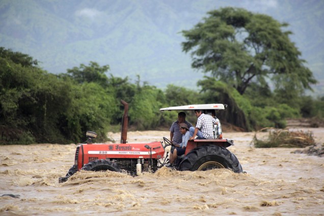 Camponeses usam um trator para atravessar as águas do Rio Zana nas proximidades da cidade de Chiclayo, ao norte de Lima no Peru. O fenômeno climático El Niño está causando o transbordamento de rios lamacentos ao longo de toda a costa peruana, isolando comunidades e bairros - 19/03/2017