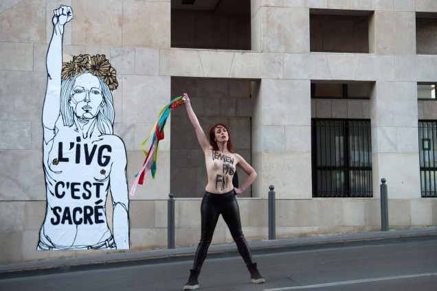 Ativista é fotografada em frente a uma obra do artista francês Mahn com a inscrição "IVG (Lei sobre o aborto voluntário) é sagrada" na Sede do Conselho Regional em Marselha, sul da França - 08/03/2017