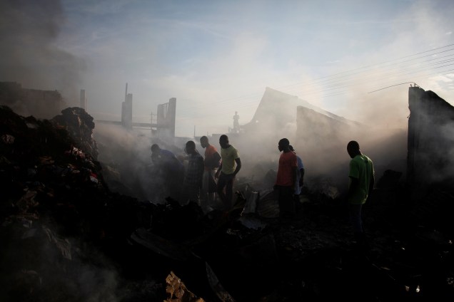 Pessoas procuram mercadorias nos escombros após um incêndio em um mercado de Porto Príncipe, no Haiti - 20/03/2017
