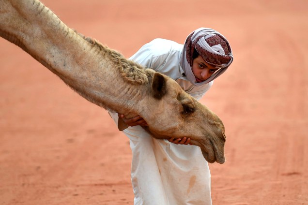 Menino posa com um camelo durante o Festival Anual de Camelos do Rei Abdul Aziz, em Rumas, Arábia Saudita - 29/03/2017
