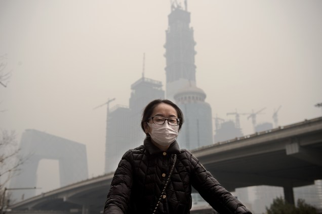 Mulher usa uma máscara protetora enquanto monta sua bicicleta em meio a um dia de intensa poluição em Pequim, na China - 20/03/2017