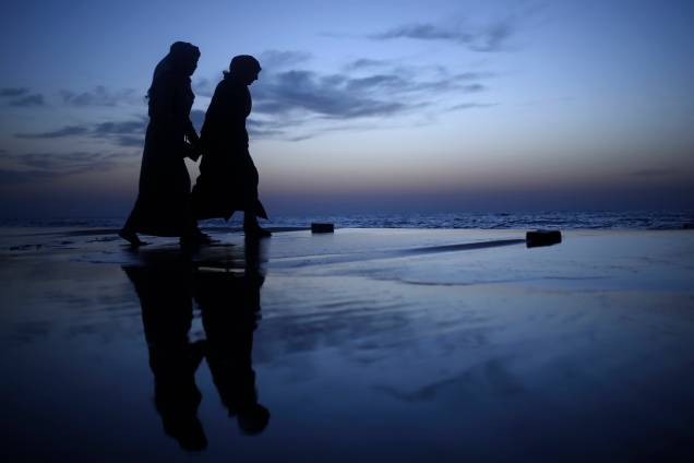 Jovens palestinas caminham de mãos dadas durante o por do sol em uma praia na cidade de Gaza - 08/03/2017 Jovens palestinas caminham de mãos dadas durante o por do sol em uma praia na cidade de Gaza - 08/03/2017