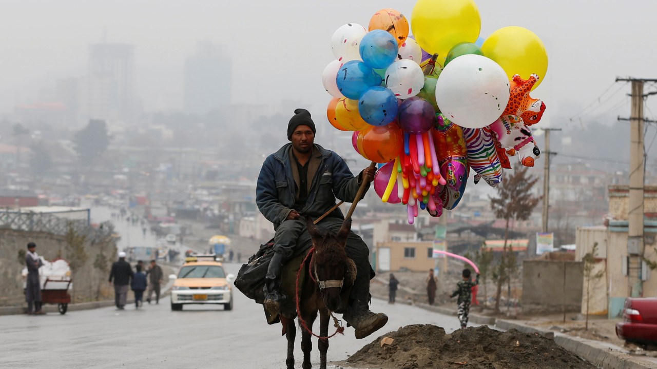 Imagens do dia - Homem vende balões em Cabul no Afeganistão