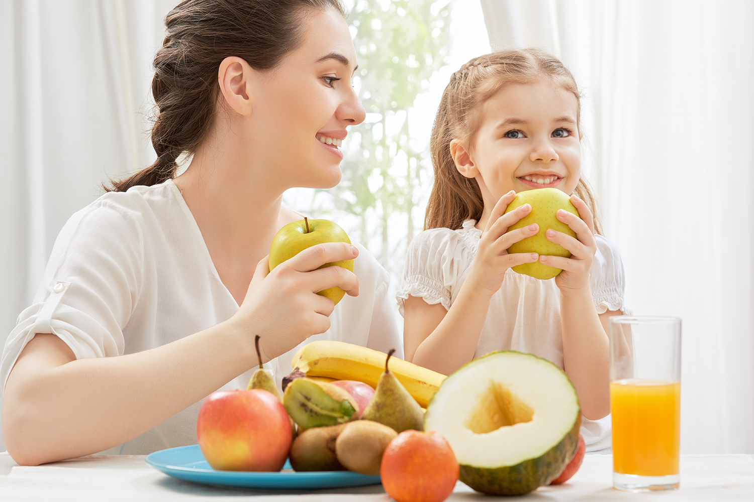 Mother and daughter eating fruit