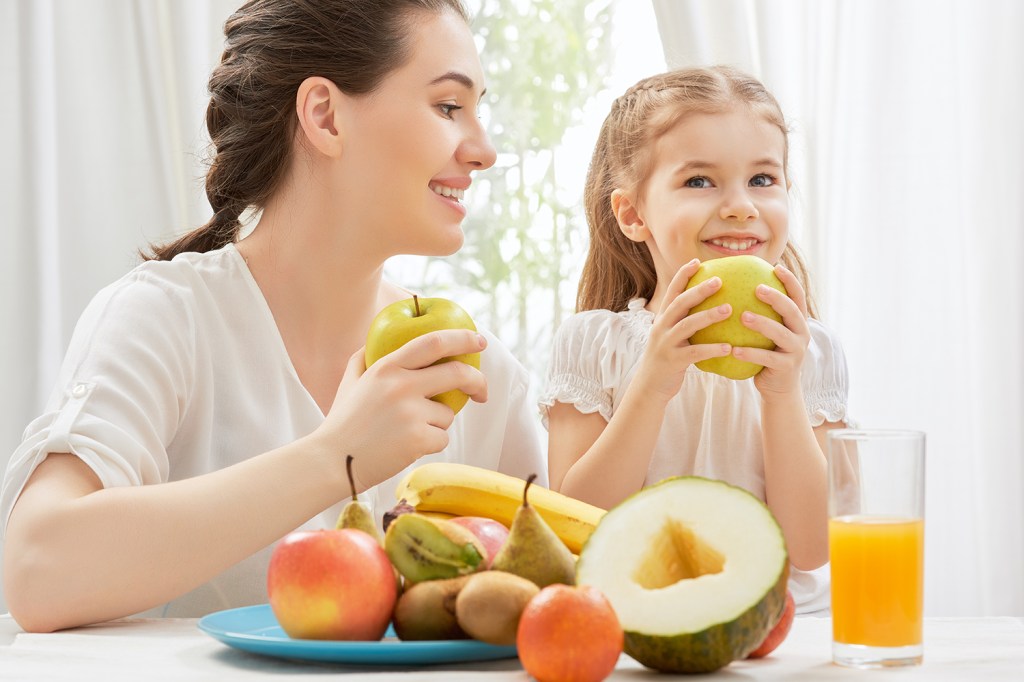 Mãe e filha comem frutas