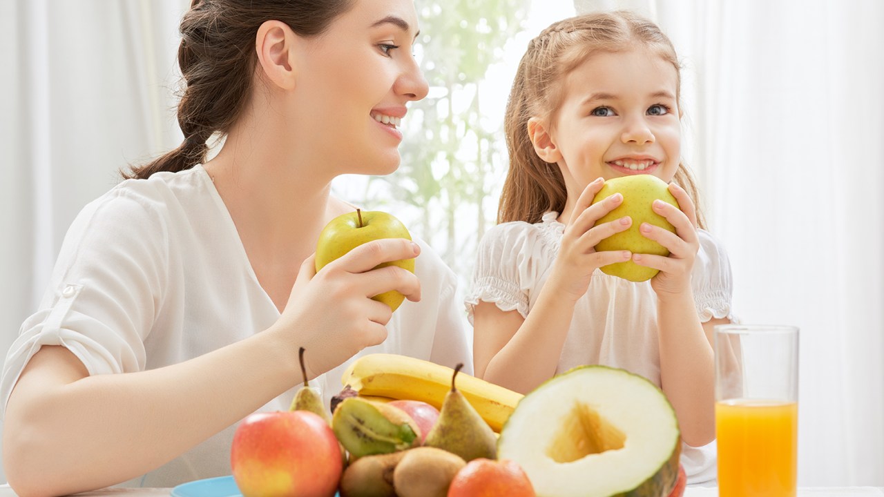 Mãe e filha comem frutas