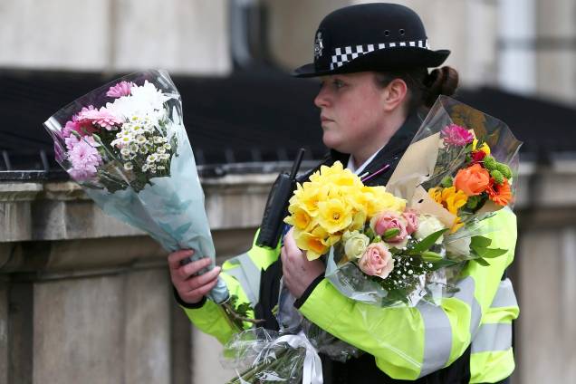Policial carrega buquês de flores em Whitehall na manhã seguinte ao ataque em Londres - 23/03/2017