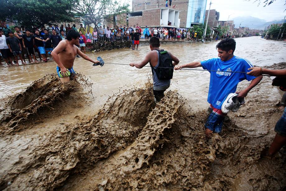 Moradores usam uma corda para atravessarem uma rua inundada na cidade de Trujillo, no Peru - 21/03/2017