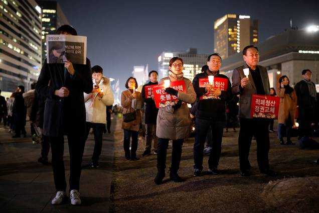 Manifestantes protestam contra a presidente Park Geun-hye, na Coreia do Sul, com cartazes que dizem "Cortemos o mal pela raiz, mudemos o regime"