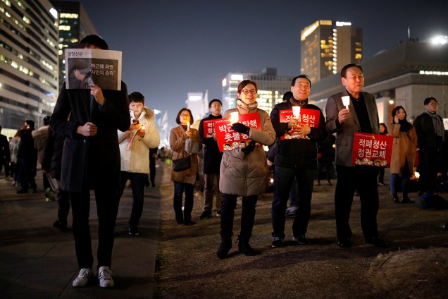 Manifestantes protestam contra a presidente Park Geun-hye, na Coreia do Sul, com cartazes que dizem "Cortemos o mal pela raiz, mudemos o regime"