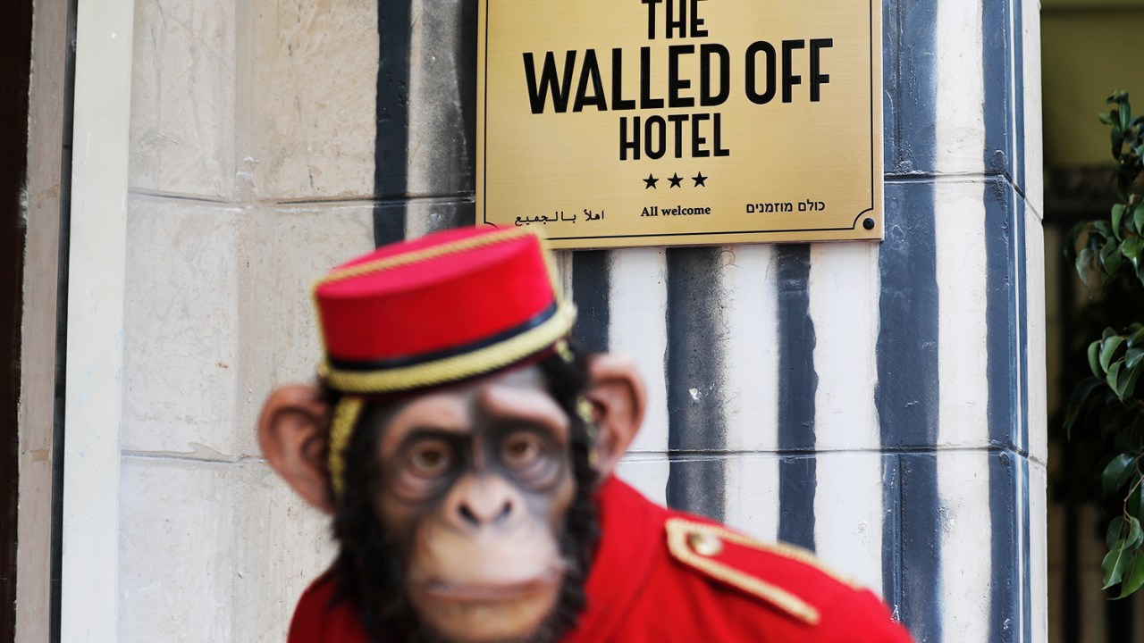 Boneco de mensageiro de hotel em forma de macaco na entrada do Walled Off, recém-inaugurado pelo artista britânico Banksy - 03/03/2017