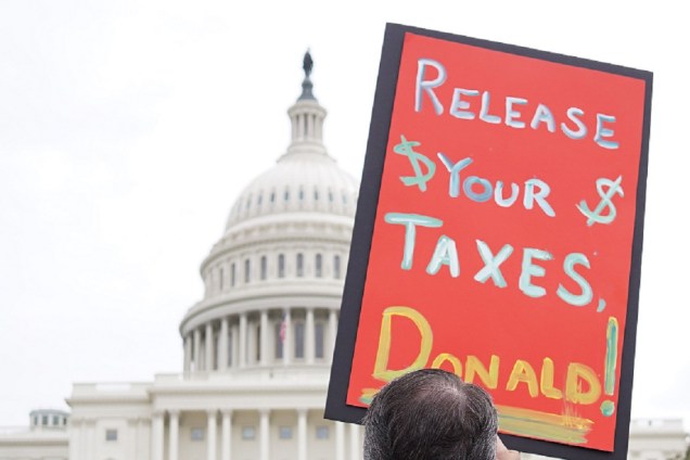 Manifestante protesta contra decisão de Donald Trump de esconder seus registros de impostos, durante ato realizado em frente ao Capitólio, em Washington