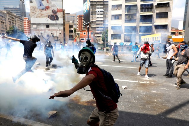 Manifestante joga gás lacrimogêneo de volta aos policiais durante o protesto em Caracas, Venezuela, contra o governo de Nicolás Maduro - 06/04/2017