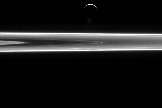 Foto tirada pela missão Cassini, da Nasa, mostra a lua Enceladus acima dos aneis de Saturno