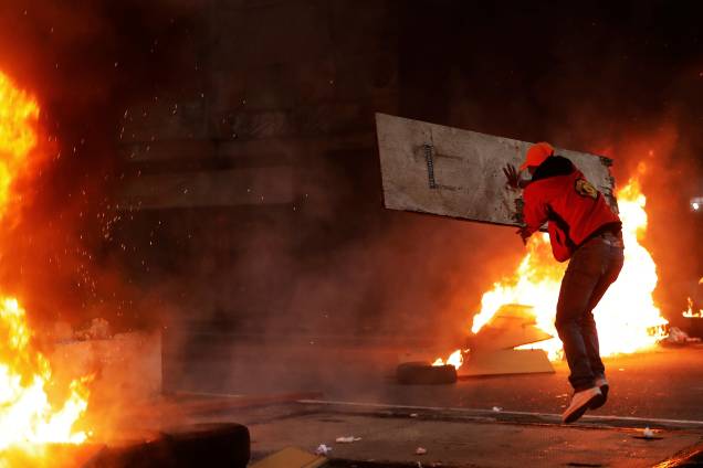 Integrante do Movimento dos Trabalhadores Sem-Teto lança um tábua de madeira sobre uma barricada em chamas durante protesto contra as reformas do governo Michel Temer em São Paulo - 28/04/2017