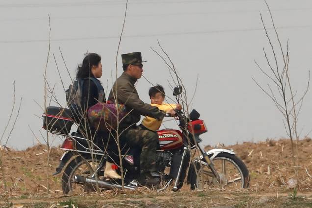 Soldado norte-coreano anda de moto com a família na fronteira com a China pelo rio Yalu, próximo a cidade de Sinuiju, na Coreia do Norte, e da província de Dandong, China  - 15/04/2017