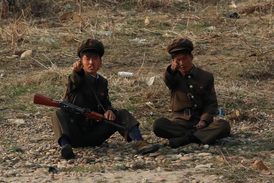 Soldados norte-coreanos gesticulam na fronteira com a China pelo rio Yalu, próximo a cidade de Sinuiju, na Coreia do Norte, e da província de Dandong, China - 15/04/2017