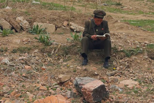 Soldado norte-coreano lê um livro próximo ao rio Yalu, que faz fronteira com a cidade próxima Dandong, na China, e com Sinuiju, na Coreia do Norte - 15/04/2017