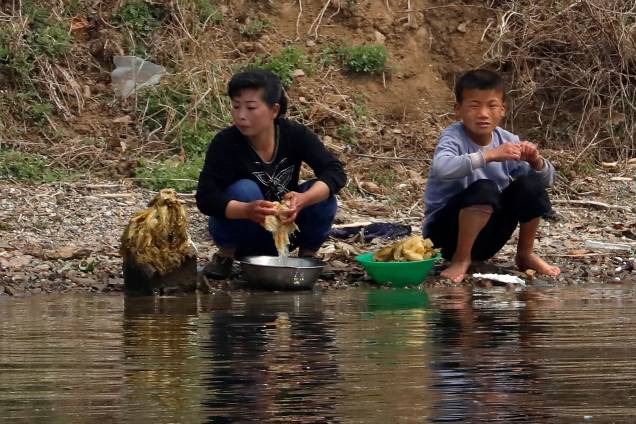 Norte-coreanos lavam alimentos no rio Yalu, que faz a fronteira de Dandong, na China, e de Sinuiju, Coreia do Norte - 16/04/2017