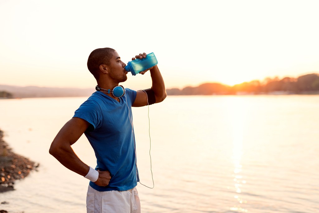 Homem se hidrata durante exercício