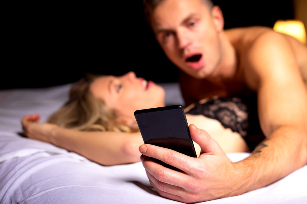 Homem olha para o celular durante o sexo