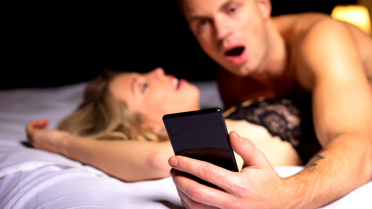 Homem olha para o celular durante o sexo