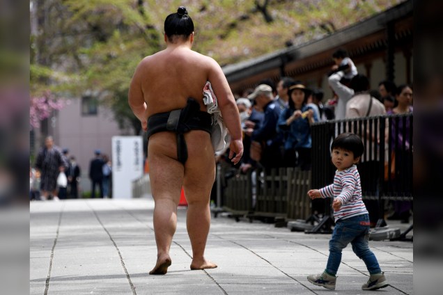 Menino segue um lutador de sumô durante evento anual com lutadores no santuário de Yasukuni em Tóquio, no Japão - 17/04/2017