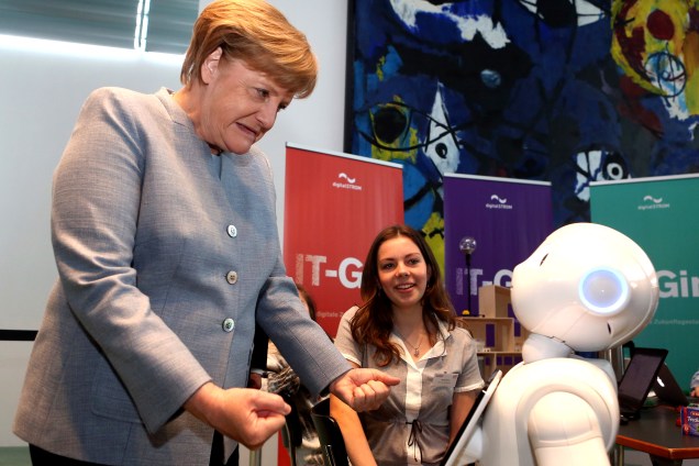 A Chanceller da Alemanha, Angela Merkel, durante o evento Dia das Meninas brincando com o robô Pepper, apresentado pela estudante Lilly Antonia em Berlim. O evento busca incentivar garotas a ingressarem em profissões de todos os tipos, principalmente em áreas científicas