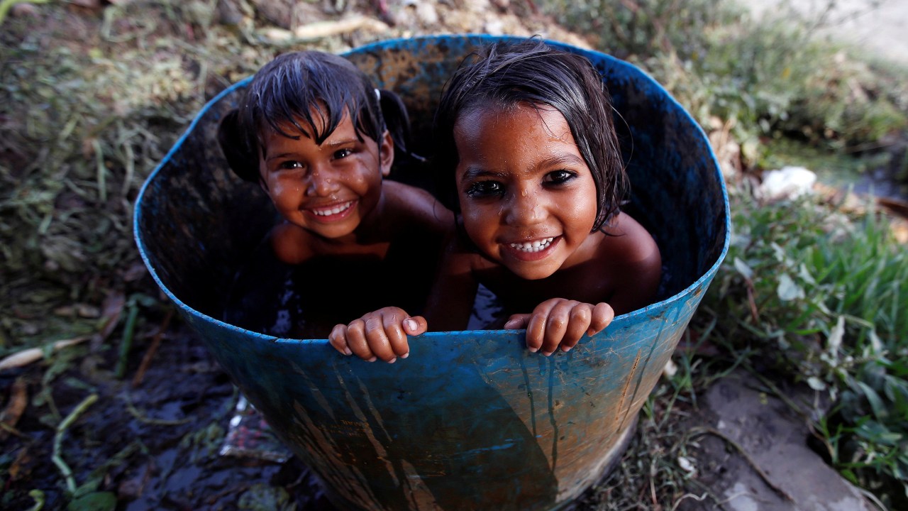 Imagens do dia - Crianças tomam banho em uma bacia na Índia