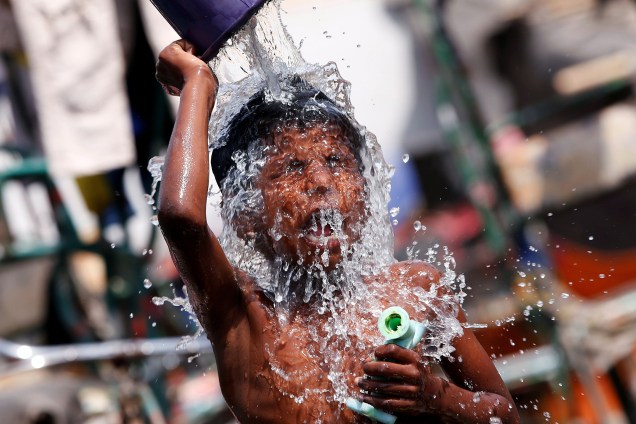 Menino se refresca do calor em uma favela em Nova Deli, na Índia - 24/04/2017