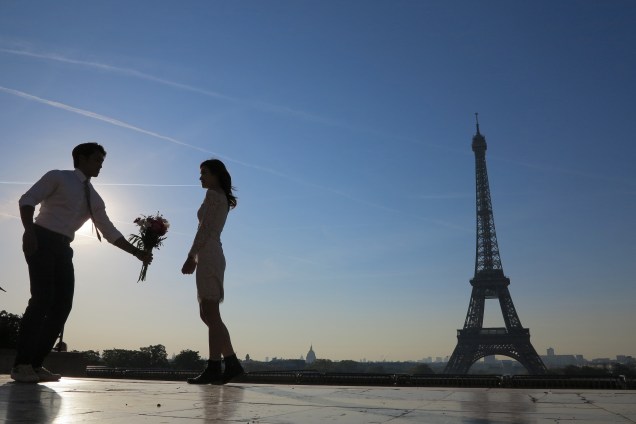 Homem oferece um ramalhete de flores para sua noiva, ao nascer do sol em frente à torre Eiffel em Paris, na França - 20/04/2017