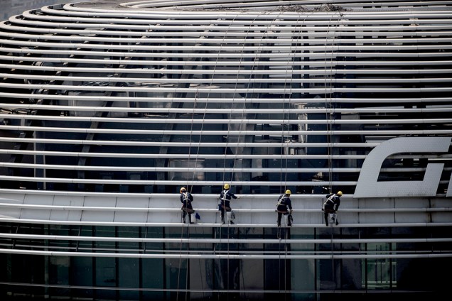 Trabalhadores limpam vidraça de prédio pelo lado de fora em Pequim, na China - 14/04/2017