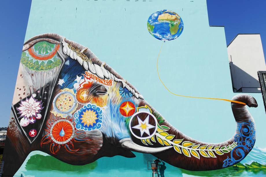 O artista alemão Jadore Tong faz os ajustes finais em um enorme mural com a imagem de um elefante colorido em Berlim, na Alemanha - 10/04/2017