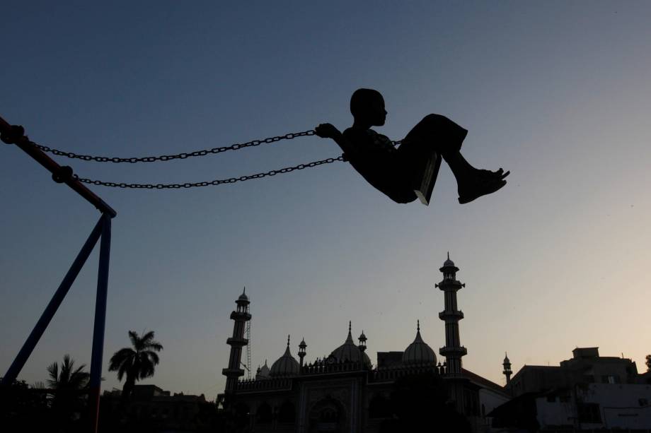 Menino brinca em um balanço durante o por do sol perto de uma mesquita em Karachi, no Paquistão - 21/04/2017