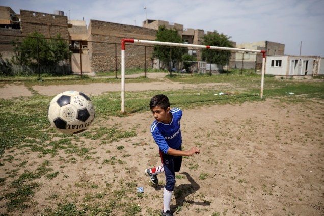Menino joga futebol em um campinho de Mosul oriental, no Iraque. A região tem sido palco dos confrontos entre forças de segurança iraquianas e jihadistas do Estado Islâmico - 21/04/2017