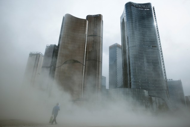 Homem caminha através de uma nuvem da poeira em um canteiro de obras em Pequim, na China - 20/04/2017