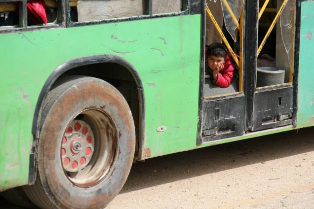 Menino é fotografado em um ônibus com civis das cidades de Fuaa e Kafraya, que está sob um cerco há mais de dois anos, enquanto esperam no ponto de trânsito de Rashidin, mantido pelos rebeldes nos arredores de Aleppo, na Síria - 21/04/2017 Menino é fotografado em um ônibus com civis das cidades de Fuaa e Kafraya, que está sob um cerco há mais de dois anos, enquanto esperam no ponto de trânsito de Rashidin, mantido pelos rebeldes nos arredores de Aleppo, na Síria - 21/04/2017