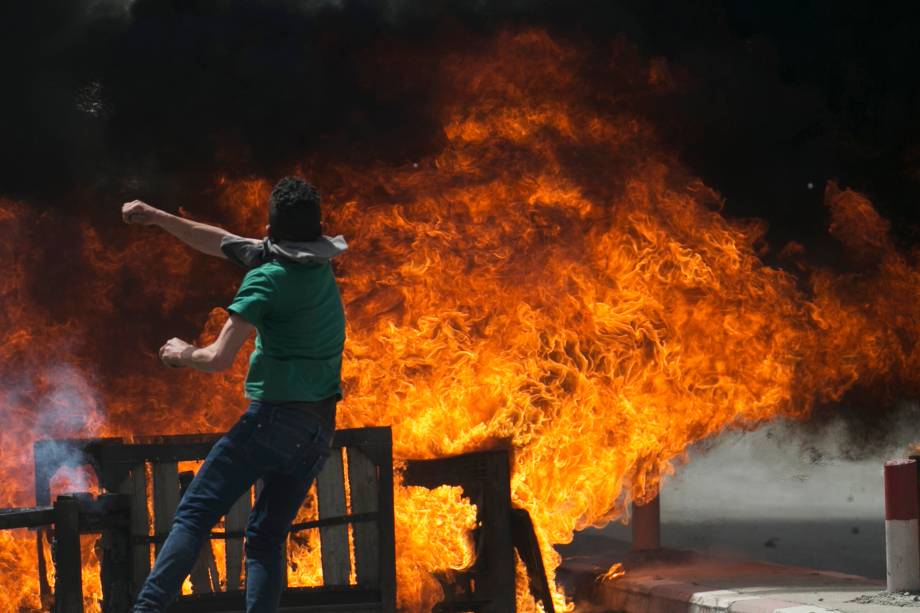 Manifestante palestino joga pedras contra forças israelenses durante confrontos na aldeia de Beita, no sudeste da cidade de Naplusa, após um protesto em solidariedade a prisioneiros palestinos em greve de fome nas prisões israelenses - 21/04/2017