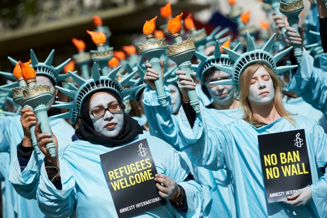 Ativistas da Anistia Internacional, vestidas como a Estátua da Liberdade, participam de uma manifestação para marcar os primeiros 100 dias do governo do Presidente dos EUA, Donald Trump, na Embaixada dos Estados Unidos em Londres - 27/04/2017