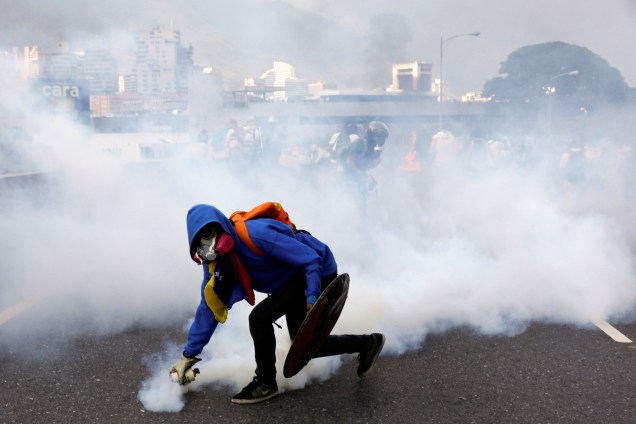 Manifestante joga uma granada de gás lacrimogêneo na polícia durante protesto contra o presidente da Venezuela, Nicolás Maduro, em Caracas - 24/04/2017