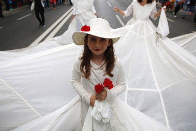 Menina segura cravos enquanto participa de um desfile em celebração ao 43˚aniversário da Revolução dos Cravos em Lisboa, Portugal - 25/04/2017