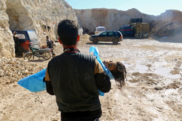 Fotógrafo carrega o corpo de uma criança morta, depois de um suposto ataque com gás na cidade de Khan Sheikhoun, na Síria - 04/04/2017