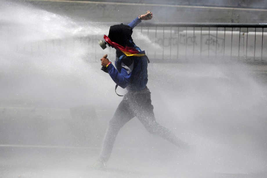 Manifestante é atingido por um canhão de água durante confronto com a polícia em uma manifestação contra o governo de Nicolás Maduro em Caracas, na Venezuela - 08/04/2017